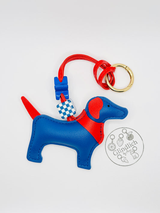 Hunde Charm in Blau und Rot. Verspielter Taschenanhänger mit goldenem Ring